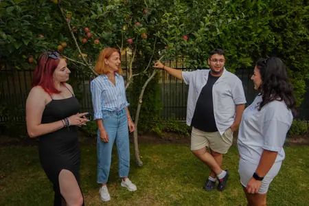 Colegi într-o livadă, unul arătând spre ceva din depărtare